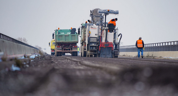 Ein Baufahrzeug hobelt auf einer Brücke den Asphalt ab.