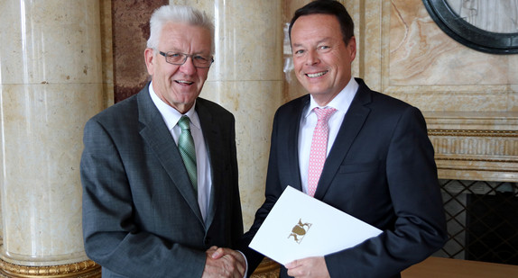 Ministerpräsident Winfried Kretschmann (l.) überreicht Klaus Tappeser (r.) die Ernennungsurkunde zum Regierungspräsidenten des Regierungsbezirks Tübingen.