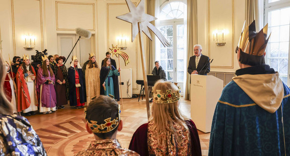 Ministerpräsident Winfried Kretschmann (hinten rechts) spricht zu den Sternsingerinnen und Sternsingern.