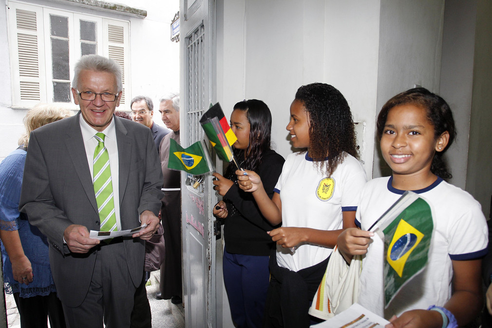 Ministerpräsident Winfried Kretschmann wird von Schülerinnen und Schülern der Hafenschule „Escola Padre Motta“ in Rio de Janeiro begrüßt. (Foto: Uli Regenscheit Fotografie)