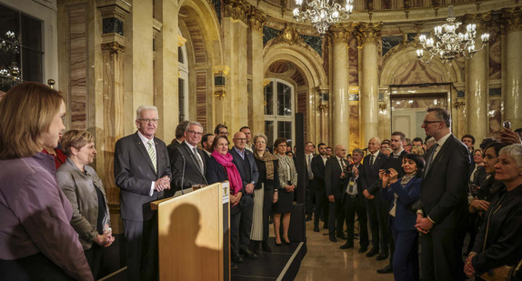 Ministerpräsident Winfried Kretschmann (Dritter von links) spricht zu den Gästen, neben ihm stehen die Mitglieder der Landesregierung.