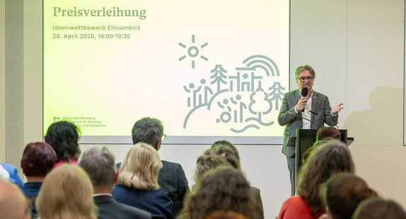 Sozialminister Manne Lucha steht vor Publikum und spricht in Mikrofon.