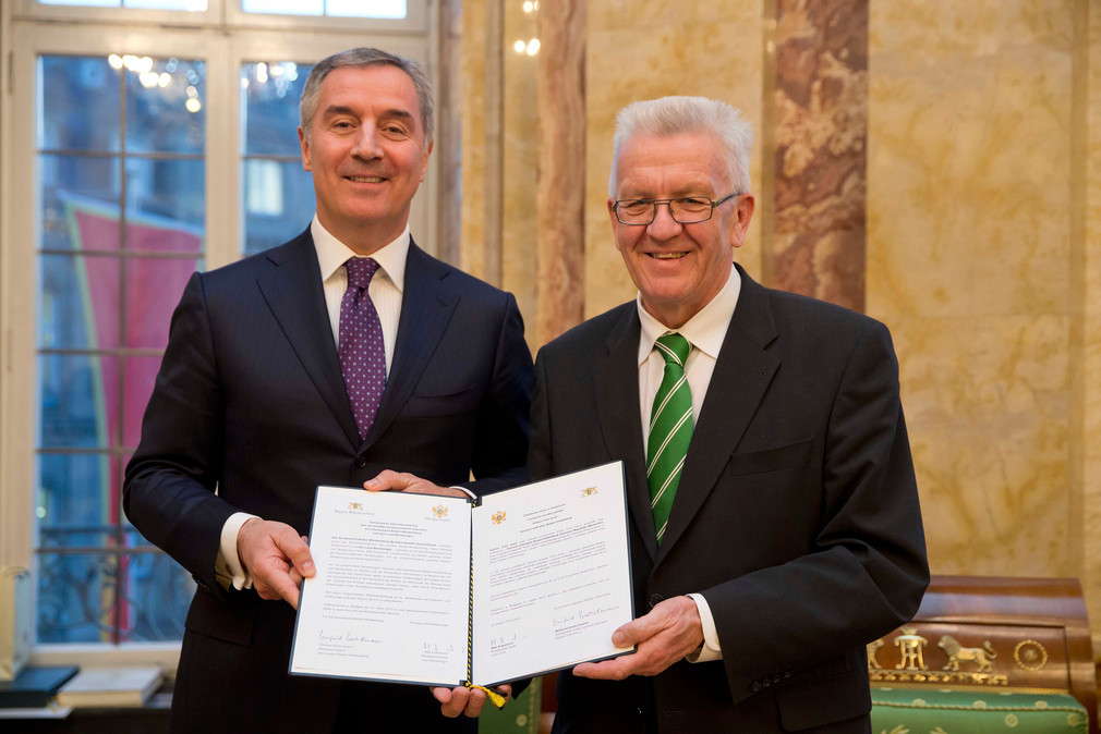 Ministerpräsident Winfried Kretschmann (r.) und der Ministerpräsident von Montenegro, Milo Đukanović (l.), mit der unterzeichneten Absichtserklärung über die künftige Zusammenarbeit zwischen Baden-Württemberg und Montenegro