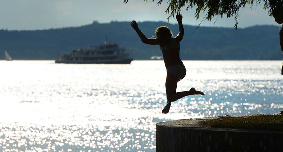 Ein Mädchen springt zur Abkühlung von der Meersburger Uferpromenade aus in den Bodensee. (Bild: dpa)