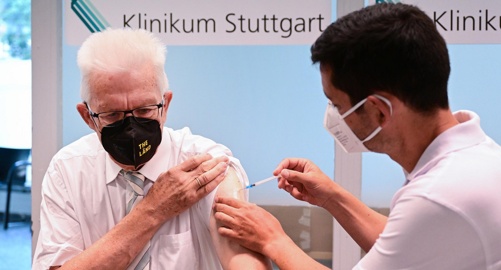 Ministerpräsident Winfried Kretschmann (links) erhält in der Impfstation im Klinikum Stuttgart vom Impfarzt Christian Menzel (rechts) seine zweite Booster-Impfung gegen das Coronavirus.