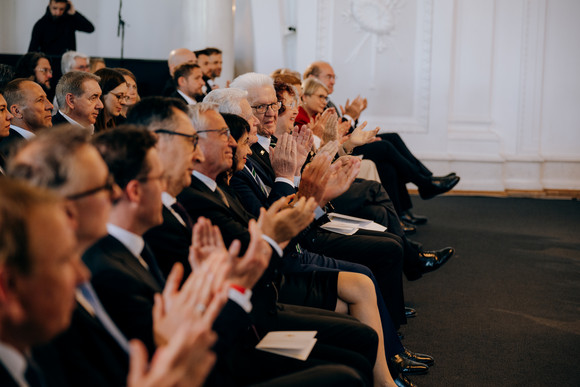 Ministerpräsident Winfried Kretschmann und die Gäste in der ersten Reihe applaudieren.