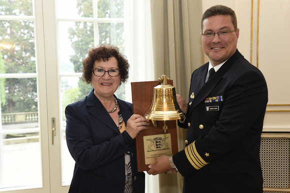 Gerlinde Kretschmann (l.) übergibt Fregattenkapitän Markus Venker (r.) eine Schiffsglocke