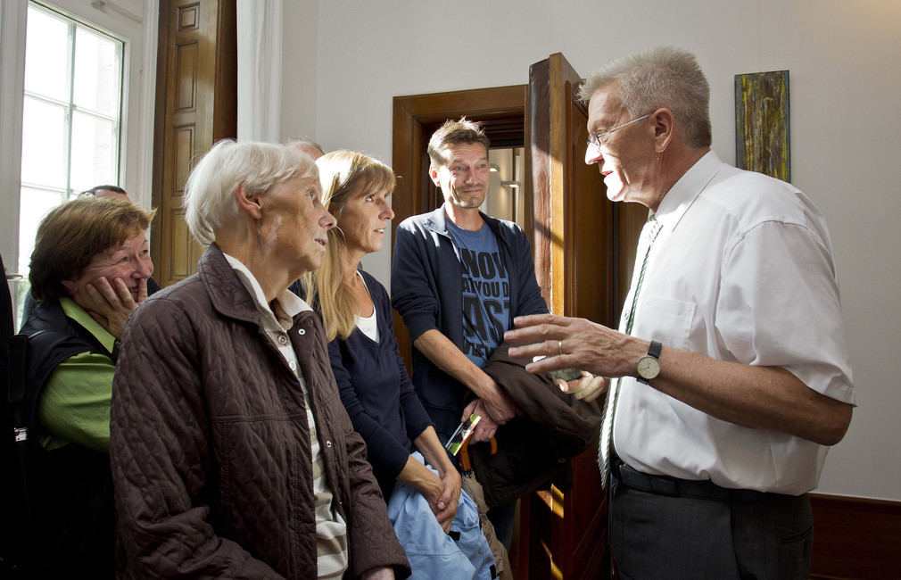 Ministerpräsident Winfried Kretschmann (r.) unterhält sich am Samstag (21.07.2012) in seinem Amtszimmer in der Villa Reitzenstein in Stuttgart mit Besucherinnen und Besuchern.
