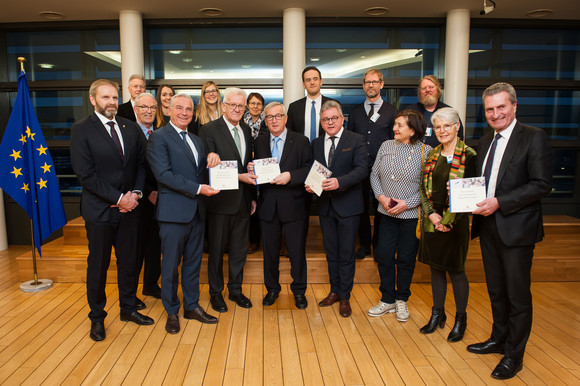 Ministerpräsident Winfried Kretschmann (vorne, 3.v.l.) übergibt EU-Kommissionspräsident Jean-Claude Juncker (vorne, 4.v.l.) Europa-Leitbild der Landesregierung (Bild: © Vertretung des Landes Baden-Württemberg bei der Europäischen Union/FKPH)