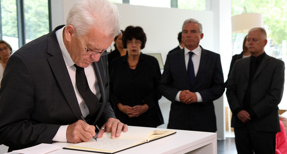 Ministerpräsident Winfried Kretschmann (l.) trägt sich in das Kondolenzbuch ein.