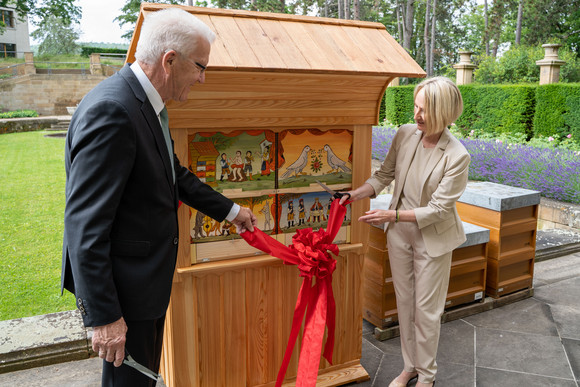 Sloweniens Generalkonsulin Dragica Urtelj (r.) überreicht Ministerpräsident Winfried Kretschmann (l.) einen traditionellen slowenischen Bienenstock.