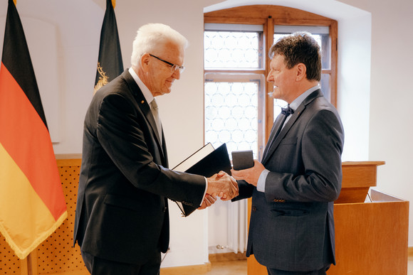 Ministerpräsident Winfried Kretschmann (links) überreicht Dr. Edwin Ernst Weber (rechts) die Staufermedaille des Landes Baden-Württemberg.