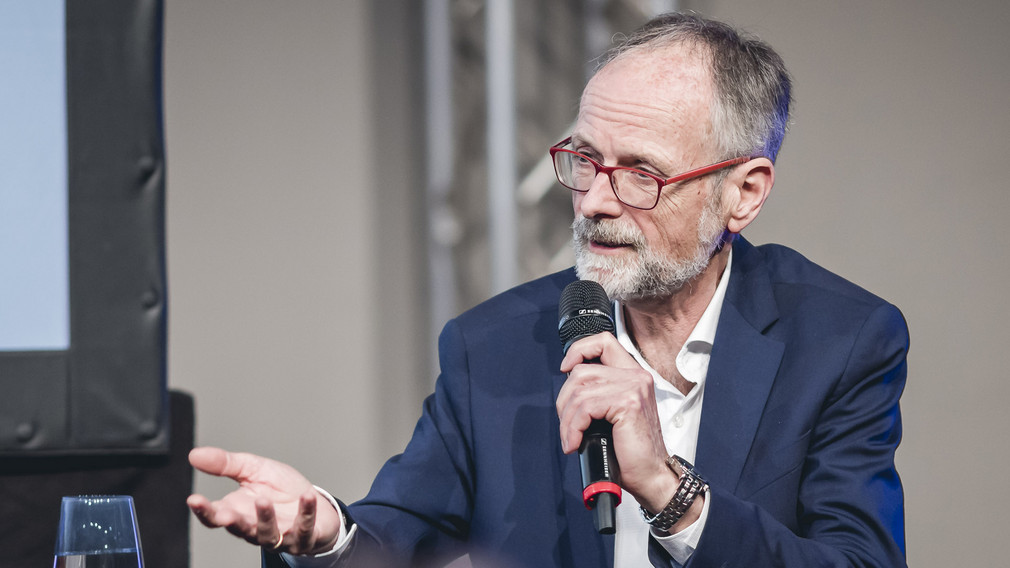 Werner Eckert, SWR-Umweltexperte hält ein Mikrofon in der Hand und spricht zu den anderen Gästen