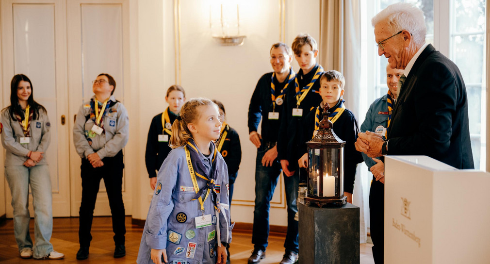 Ministerpräsident Winfried Kretschmann (rechts) mit Pfadfinderinnen und Pfadfindern bei der Übergabe des Friedenslichts