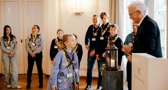 Ministerpräsident Winfried Kretschmann (rechts) mit Pfadfinderinnen und Pfadfindern bei der Übergabe des Friedenslichts