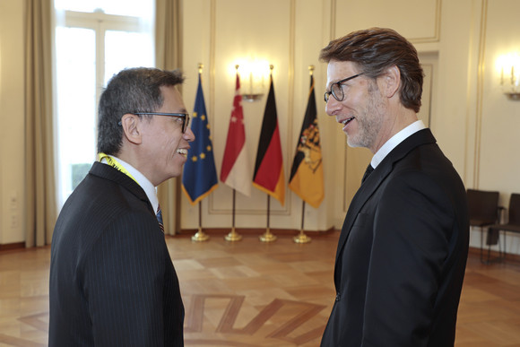 Internationales Stegmann empfängt Botschafter von Singapur Staatsminister Dr. Florian Stegmann (rechts) und der Botschafter der Republik Singapur, Lee Chong Hock (links) im Gespräch. Im Hintergrund stehen Fahnen.