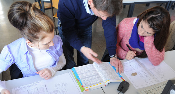 Ein Lehrer erklärt Schülerinnen etwas im Unterricht (Bild: © Ministerium für Kultus, Jugend und Sport BW).