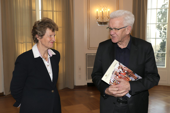 Die Vorsitzende des Normenkontrollrats Baden-Württemberg, Dr. Gisela Meister-Scheufelen (l.), übergibt Ministerpräsident Winfried Kretschmann (r.) eine Studie zur Bürokratieentlastung im Ehrenamt. (Bild: Staatsministerium Baden-Württemberg)