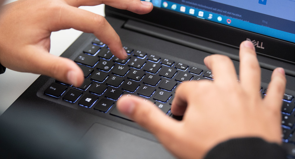 Ein Schüler nimmt am Unterricht mit Hilfe von einem Laptop teil.