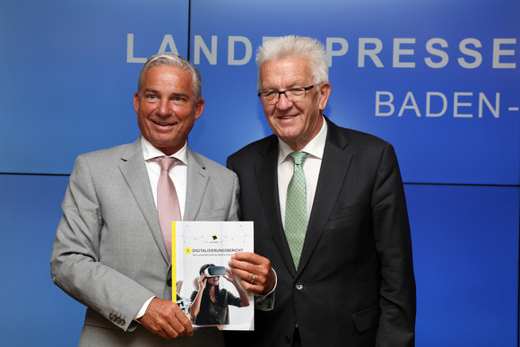 Ministerpräsident Winfried Kretschmann (r.) und Digitalisierungsminister Thomas Strobl (l.) mit einer gedruckten Version des ersten Digitalisierungsberichts der Landesregierung Baden-Württemberg