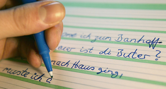 Ein Analphabet schreibt Sätze zur Übung in ein Schulheft (Bild: © dpa)