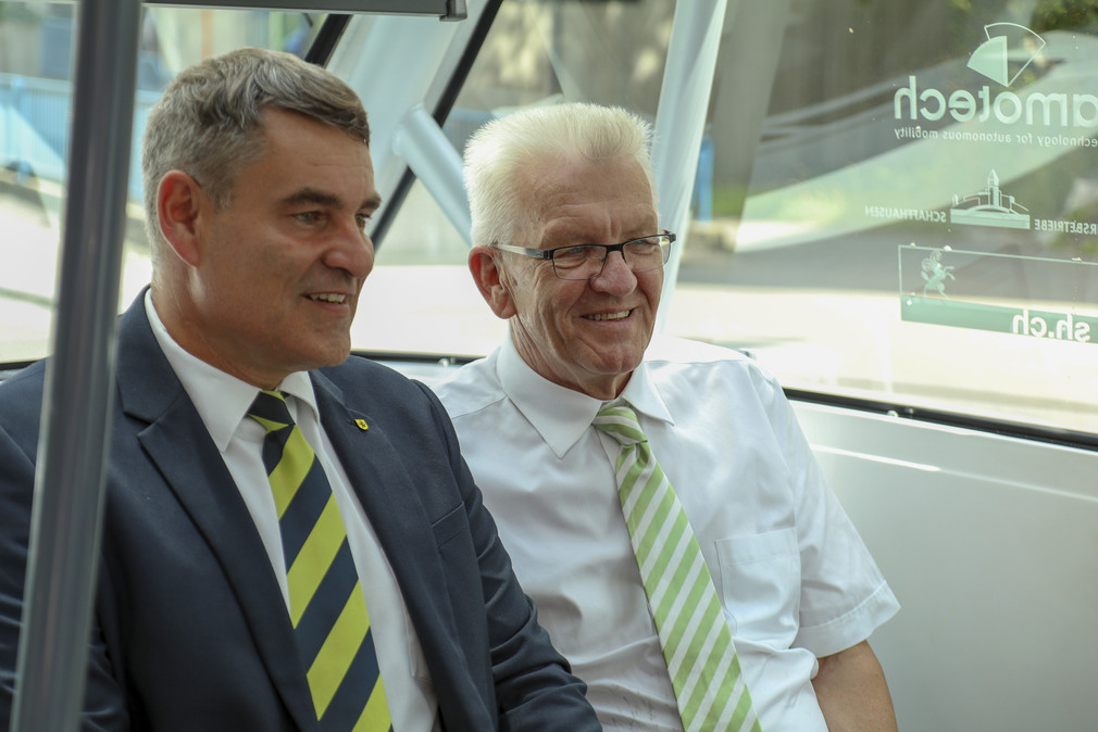 Ministerpräsident Winfried Kretschmann (r.) und Christian Amsler (l.), Regierungspräsident des Kantons Schaffhausen, sitzen in einem autonom fahrenden Bus der Verkehrsbetriebe Schaffhausen.