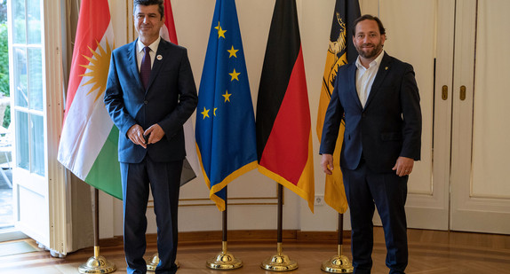 Staatssekretär Florian Hassler (r.) und der Gouverneur der Provinz Dohuk, Prof. Dr. Ali Tatar Nerway (l.) stehen vor Fahnen.