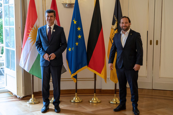 Gespräch Hassler trifft Gouverneur der Provinz Dohuk Staatssekretär Florian Hassler (r.) und der Gouverneur der Provinz Dohuk, Prof. Dr. Ali Tatar Nerway (l.) stehen vor Fahnen.