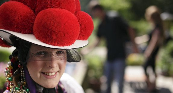 Eine junge Frau trägt einen traditionellen Bollenhut.