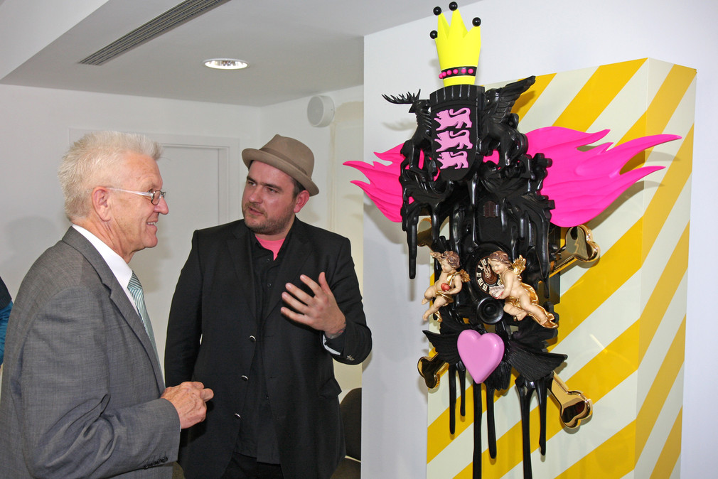 Der Künstler Stefan Strumbel (l.) und Ministerpräsident Winfried Kretschmann (r.) mit dem Kunstwerk „Heimat großer Kunst“