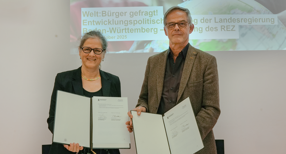 Entwicklungspolitik Hoogvliet unterzeichnet Memorandum of Understanding mit finep Petra Schmettow, Vorständin von finep und Rudi Hoogvliet, Staatssekretär für Medienpolitik und Bevollmächtigter des Landes Baden-Württemberg beim Bund halten die unterzeichneten Verträge in die Kamera