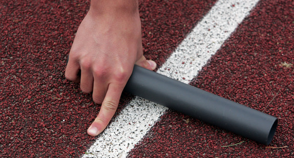 Ein Startläufer einer 4x100m-Staffel hält einen Staffelstab in der Hand.