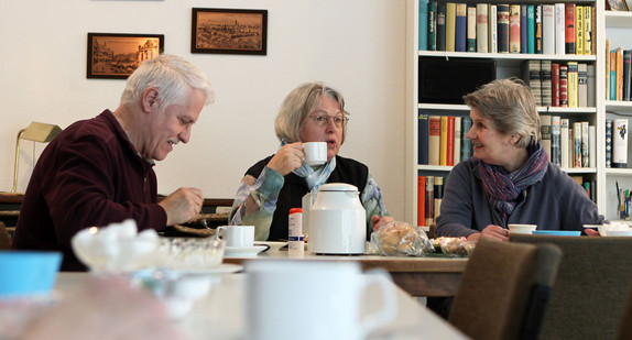 Die Bewohnerin (r) einer Wohngemeinschaft für Senioren unterhält sich bei Kaffee und Kuchen mit ihren Gästen (Bild: © dpa).