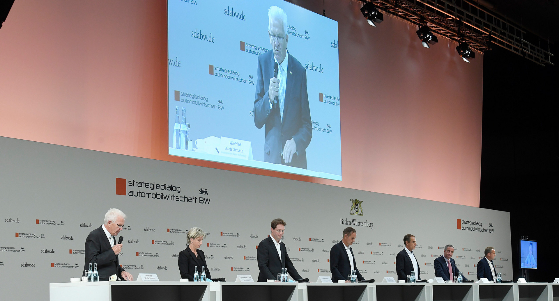 v.l.n.r.: Ministerpräsident Winfried Kretschmann spricht auf der gemeinsamen Pressekonferenz mit Wirtschaftsministerin Nicole Hoffmeister-Kraut, Ola Källenius, Vorstandsvorsitzender der Daimler AG und der Mercedes-Benz AG, Oliver Blume, Vorstandsvorsitzender der Porsche AG, Volkmar Denner, Vorsitzender der Geschäftsführung der Robert Bosch GmbH, Frank Mastiaux, Vorstandsvorsitzender der EnBW, Roman Zitzelsberger, Bezirksleiter der IG Metall Baden-Württemberg, und Brigitte Dahlbender (Video), Landesvorsitzende des Bundes für Umwelt und Naturschutz Deutschland (BUND) Baden-Württemberg