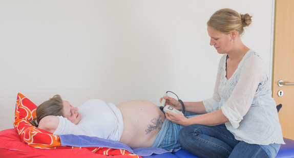 Eine Hebamme führt eine Ultraschalluntersuchung an einer Schwangeren durch.