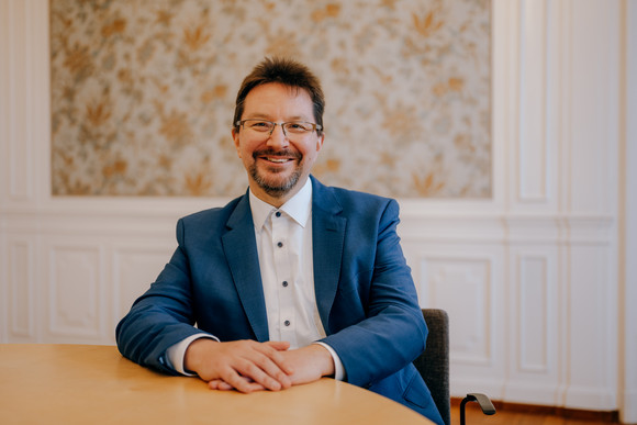 Porträtbild von Dr. Michael Blume, an einem Tisch sitzend.
