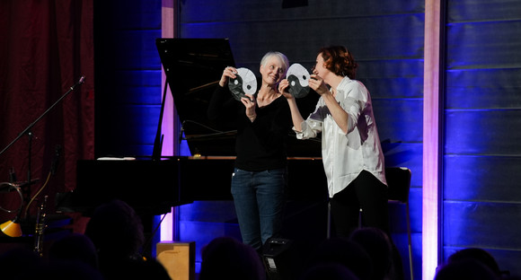 Jaana Felicitas (rechts) und eine Gästin des Abends performen gemeinsam einen Zaubertrick auf der Bühne