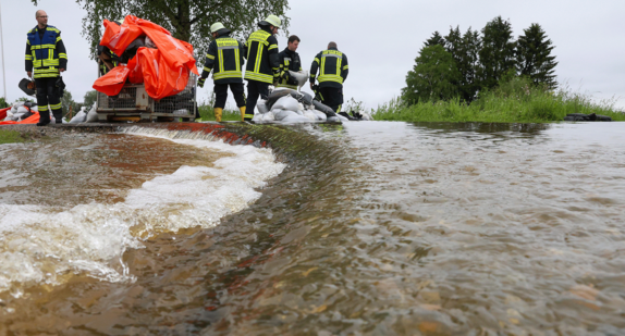 Einsatzkräfte der Feuerwehr errichten am Nonnenbach in Bad Saulgau im Ortsteil Moosheim einen Damm mit Sandsäcken gegen das Hochwasser.