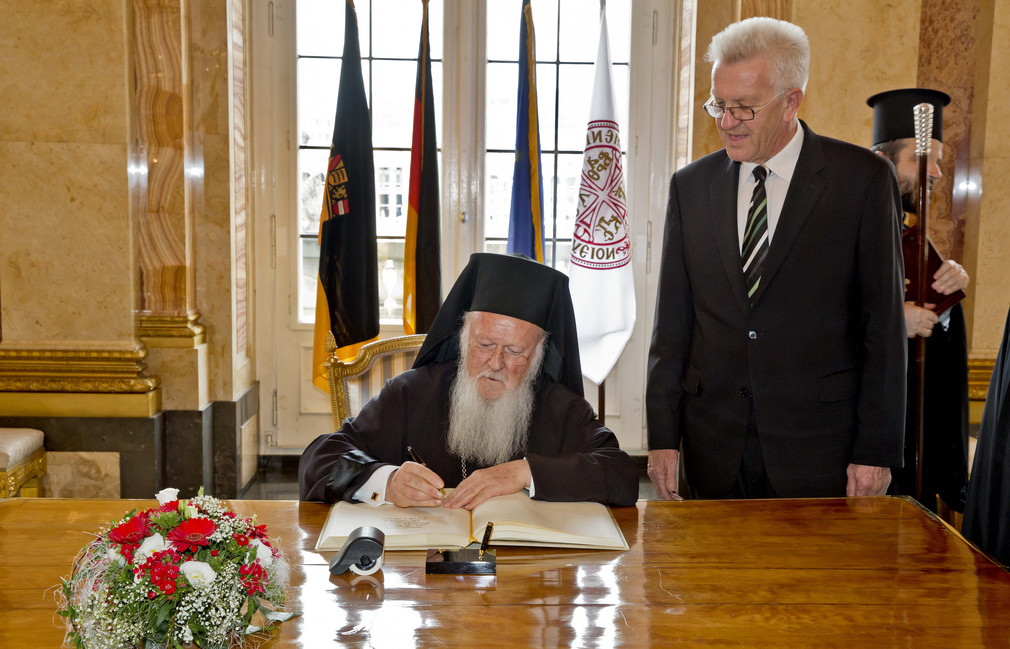 Patriarch Bartholomaios (l.) beim Eintrag in das Gästebuch der Landesregierung und Ministerpräsident Winfried Kretschmann (r.)