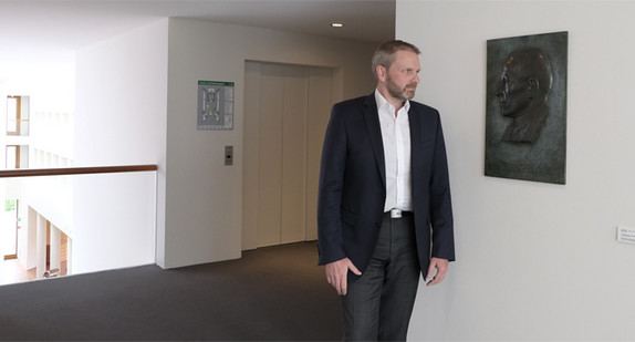 Staatssekretär Volker Ratzmann steht vor der Bronzeportraittafel zum Gedenken an Eugen Bolz (Foto: Landesvertretung Baden-Württemberg Berlin)