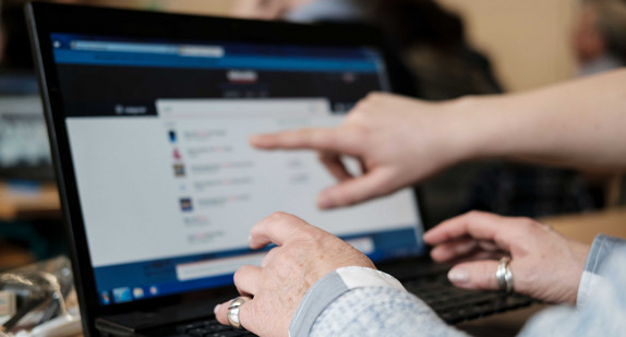 Eine ältere Dame lernt die Bedienung eines Computers.