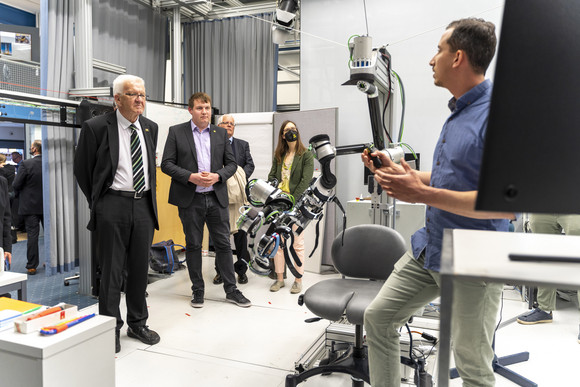 Ministerpräsident Winfried Kretschmann (links) ist beim Besuch der Eidgenössischen Technischen Hochschule Zürich (ETH Zürich) mit anderen Personen in einem Labor.