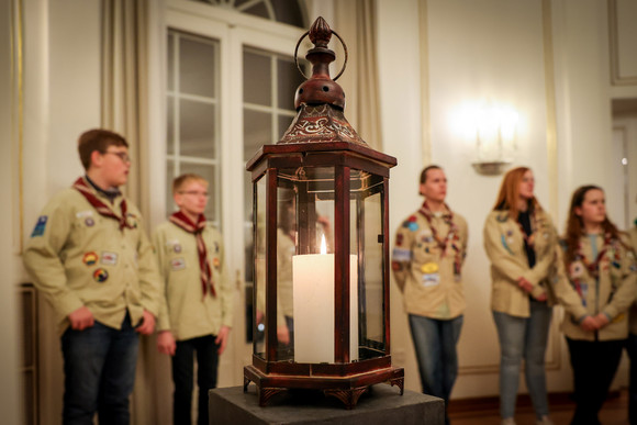 Das Friedenslicht aus Bethlehem, im Hintergrund stehen Pfadfinderinnnen und Pfadfinder.