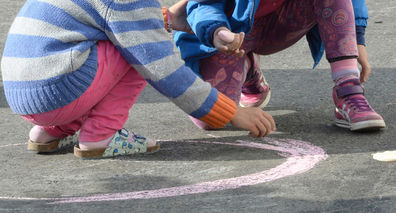 Zwei Kinder malen mit Kreide auf Straßenboden