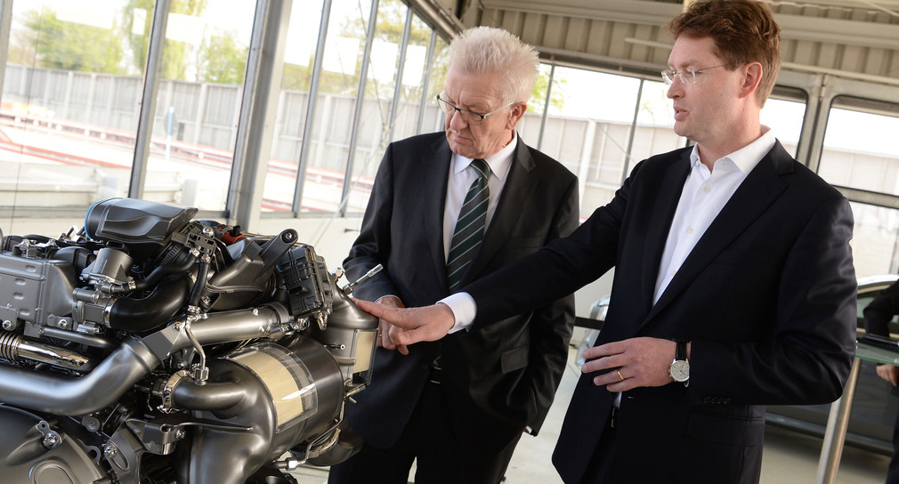 Ministerpräsident Winfried Kretschmann (l. und Ola Källenius (r.), Daimler Vorstand Konzernforschung & Mercedes-Benz Cars Entwicklung, betrachten einen Dieselmotor. (Foto: ©dpa)