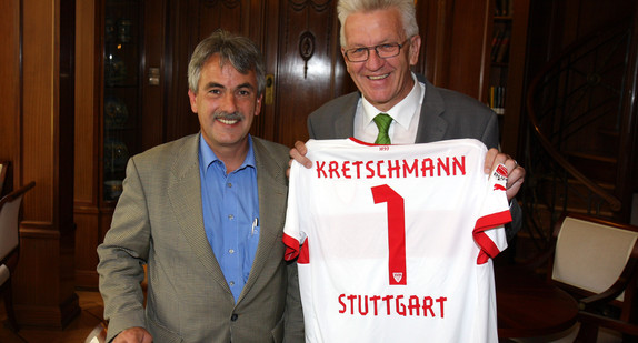 Gerd E. Mäuser (l.), Präsident des VfB Stuttgart, und Ministerpräsident Winfried Kretschmann (r., mit einem Trikot des VfB Stuttgart mit dem Aufdruck "Kretschmann 1 Stuttgart" in der Hand) am 29. Juni 2012 in der Villa Reitzenstein in Stuttgart