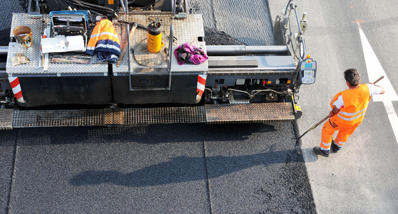 Eine neue Asphaltdecke wird auf einer Straße aufgebracht. (Bild: Patrick Seeger / dpa)