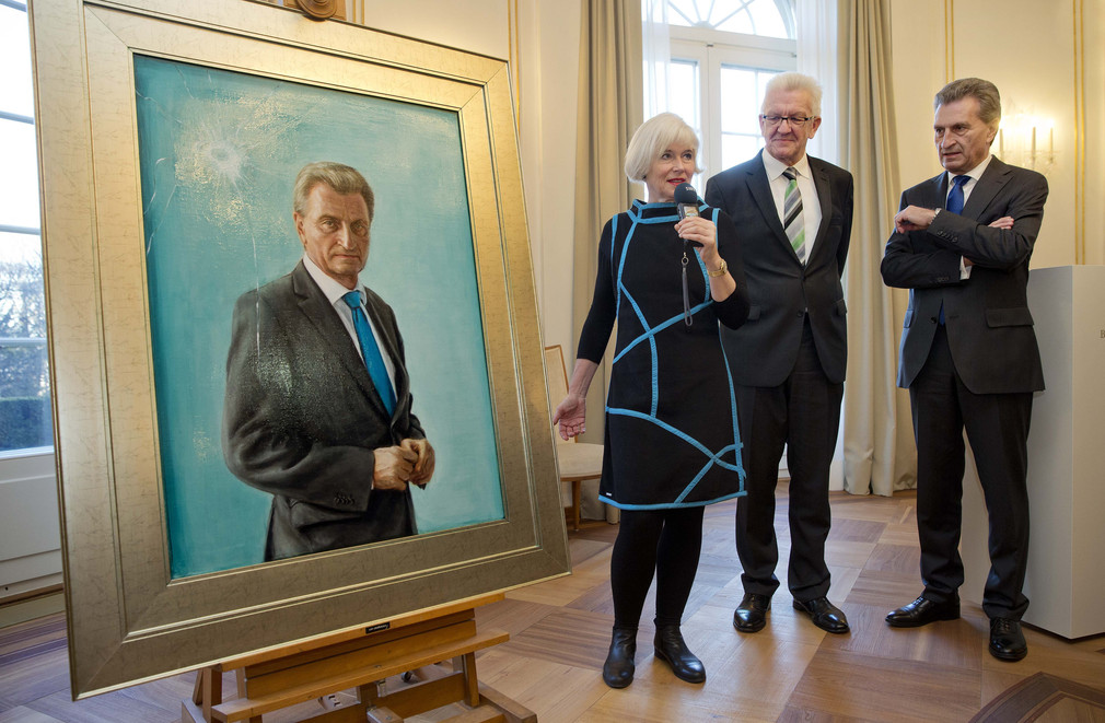 v.l.n.r.: Die Künstlerin Anke Doberauer, der ehemalige Ministerpräsident Günther Oettinger und Ministerpräsident Winfried Kretschmann stehen neben dem Porträt von Günther Oettinger.
