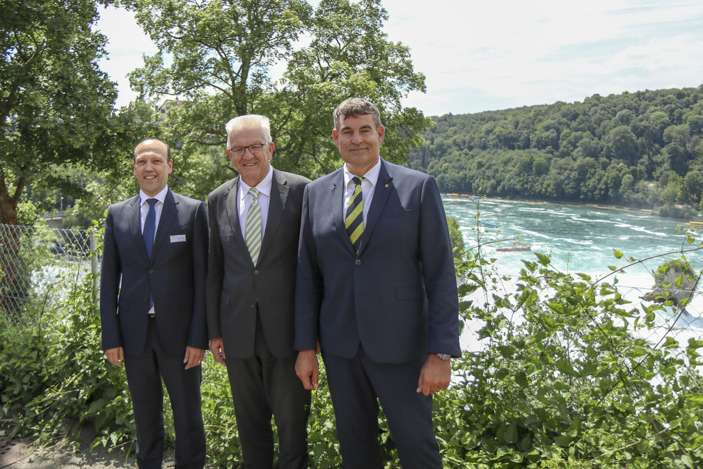 Christian Amsler (r.), Regierungspräsident des Kantons Schaffhausen, Ministerpräsident Winfried Kretschmann (M.) und Peter Schneck (l.), CEO Trapeze Switzerland, am Rheinfall in Schaffhausen