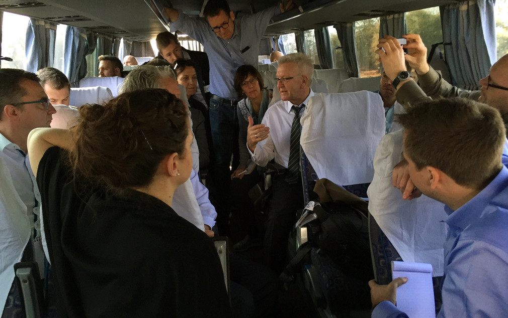 Ministerpräsident Winfried Kretschmann (M.) beim Pressegespräch mit Journalisten in einem Bus